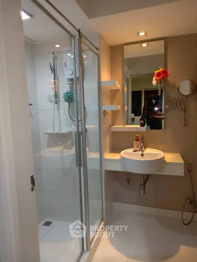Modern bathroom with glass shower enclosure and stylish sink area.