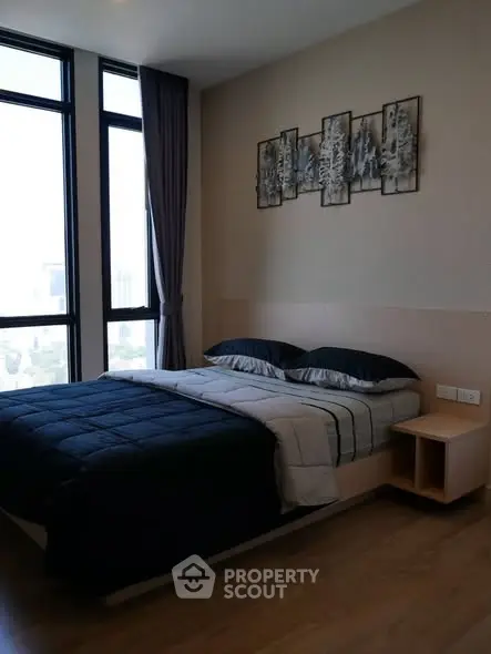Modern bedroom with large windows and stylish decor in a high-rise apartment.