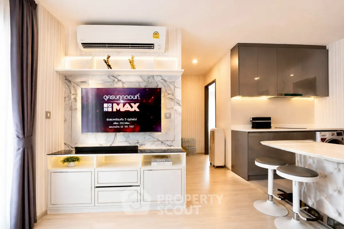 Modern living room with sleek TV setup and stylish kitchen in open layout apartment.