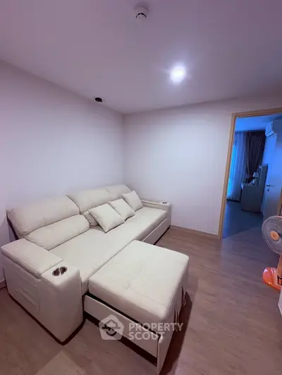 Cozy living room with modern beige sofa and wooden flooring, perfect for relaxation.