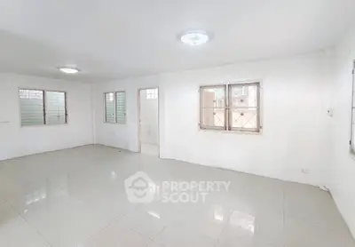 Spacious white-tiled room with large windows and bright lighting, perfect for versatile living space.