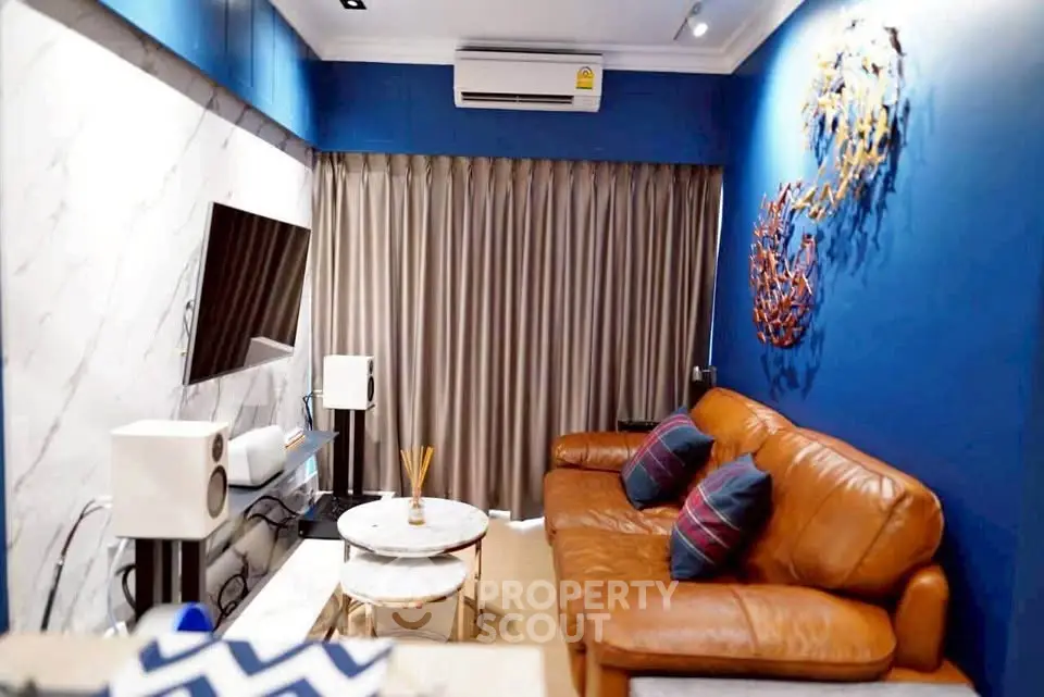 Stylish living room with leather sofa, modern decor, and wall-mounted TV in a cozy apartment.