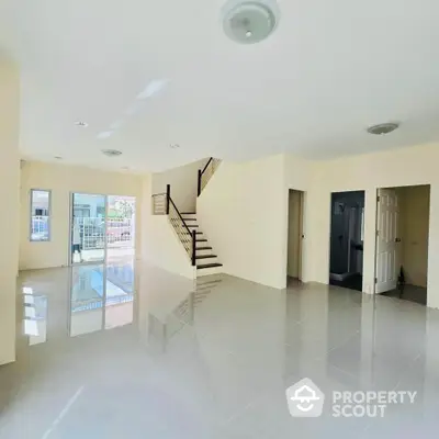 Spacious modern living room with glossy tile flooring and staircase