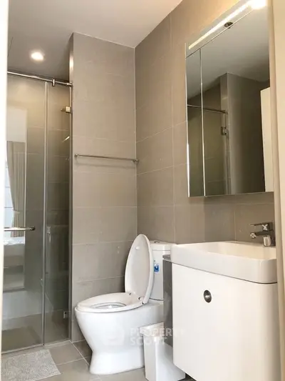 Modern bathroom with sleek fixtures and glass shower enclosure in contemporary apartment.