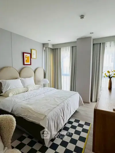 Modern bedroom with stylish decor and natural light, featuring a cozy bed and elegant furnishings.