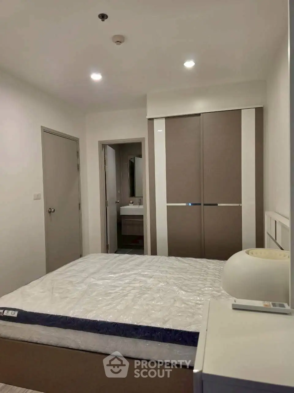 Modern bedroom with sleek wardrobe and cozy lighting in a stylish apartment.