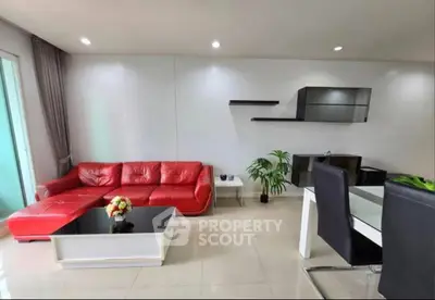 Modern living room with red leather sofa and sleek dining area in open layout apartment.
