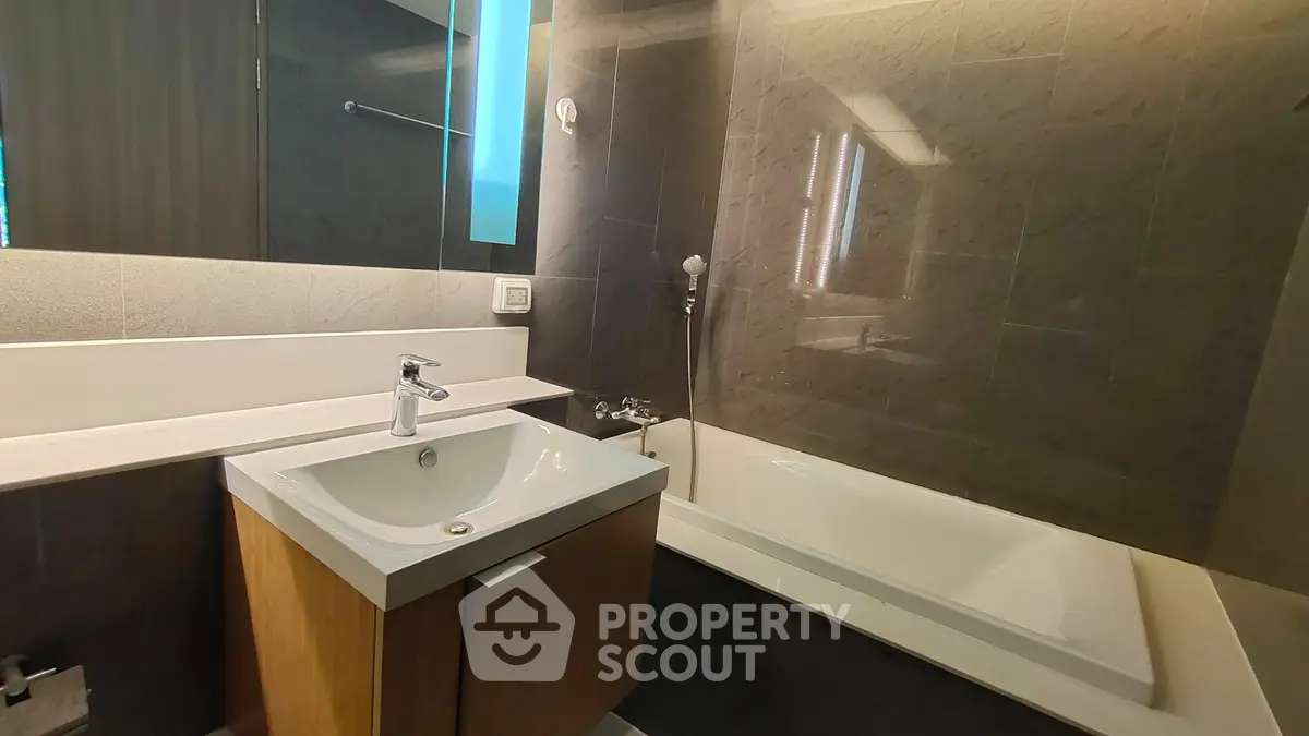 Modern bathroom with sleek design, featuring a bathtub and stylish vanity.