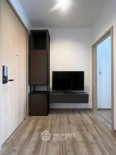 Modern minimalist living room with wooden flooring and sleek TV setup.