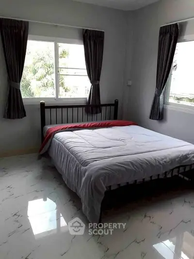 Spacious bedroom with large windows and elegant curtains, featuring a comfortable bed and modern flooring.