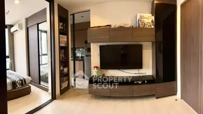 Modern living room with sleek entertainment center and view into cozy bedroom