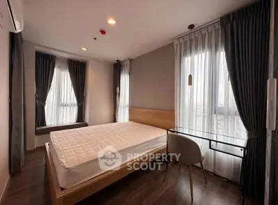 Modern bedroom with large windows and stylish furnishings in a high-rise apartment.