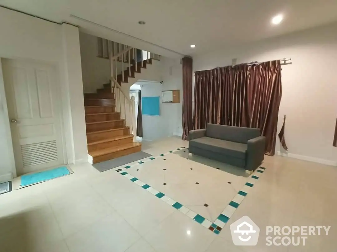 Spacious living room with gleaming tiled floors, elegant staircase, and modern furnishings, perfect for family gatherings and entertaining guests.