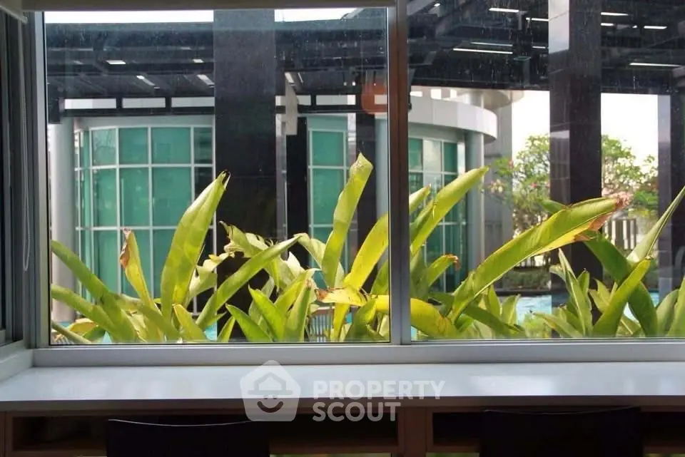 Modern building exterior with lush greenery and large windows, offering a serene view.