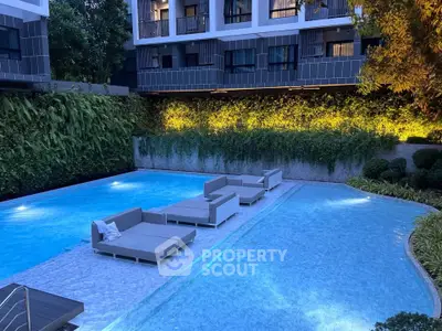 Luxurious apartment complex with stunning pool and modern outdoor seating area.