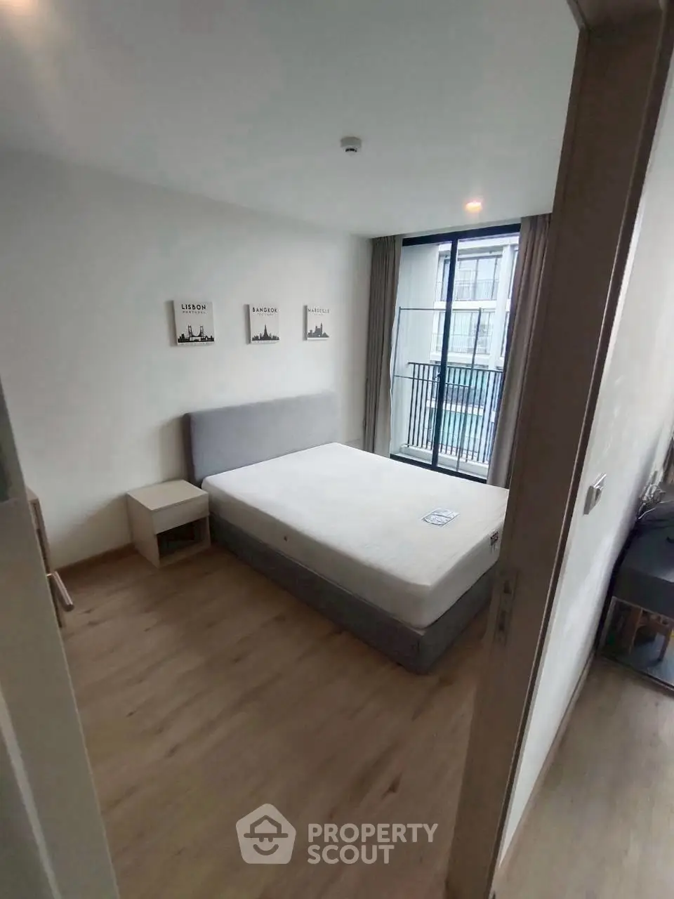 Modern bedroom with large window and minimalist decor, perfect for urban living.