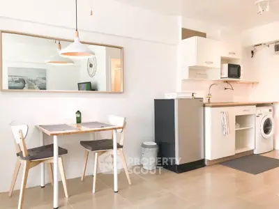 Modern kitchen and dining area with washing machine and microwave in bright apartment.