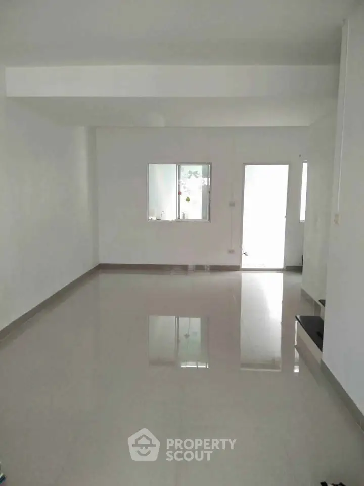 Spacious empty room with glossy tiled floor and natural light from windows.