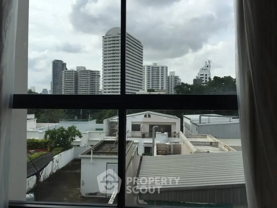 Stunning urban view from a window overlooking city skyline and rooftops, perfect for city living enthusiasts.