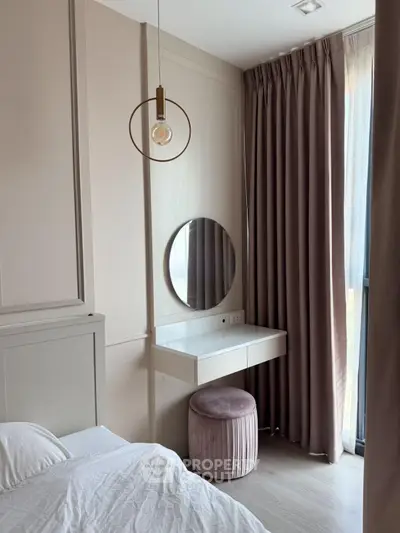 Elegant bedroom with modern pendant light and plush curtains, featuring a stylish vanity area.
