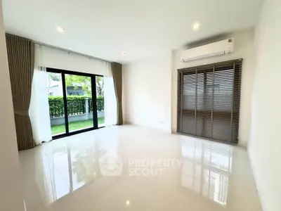 Spacious living room with large windows and garden view, featuring modern air conditioning and elegant curtains.
