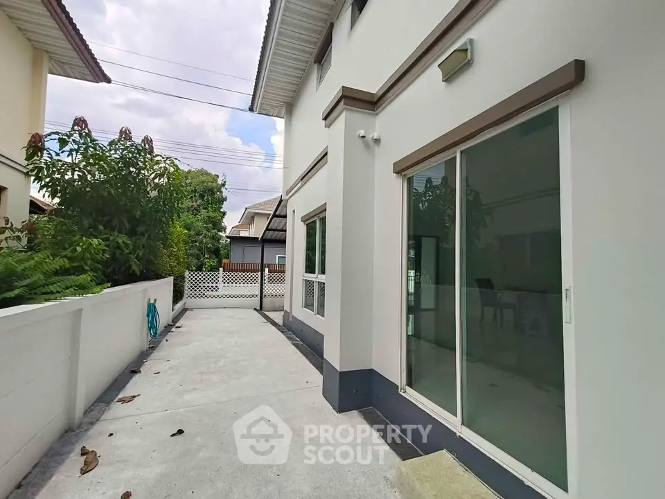 Modern house exterior with sliding glass doors and spacious driveway.