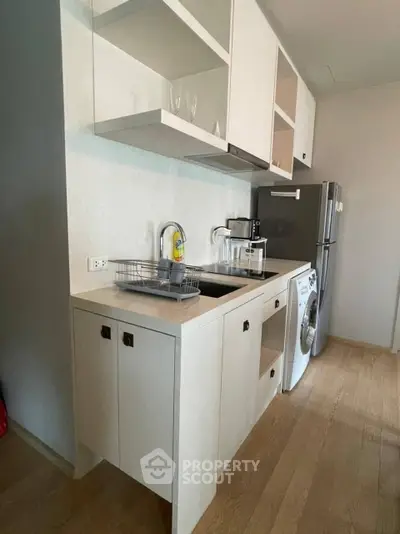 Modern compact kitchen with washing machine and fridge in sleek apartment