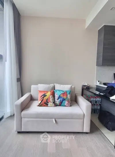 Modern living room with cozy sofa and vibrant pillows, featuring sleek wooden flooring and natural light.