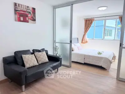 Modern apartment with sliding glass doors separating living room and bedroom, featuring stylish decor.