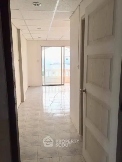 Spacious room with tiled flooring and large window leading to a balcony, perfect for natural light.