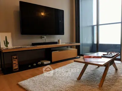 Modern living room with sleek TV setup and stylish coffee table near a large window.