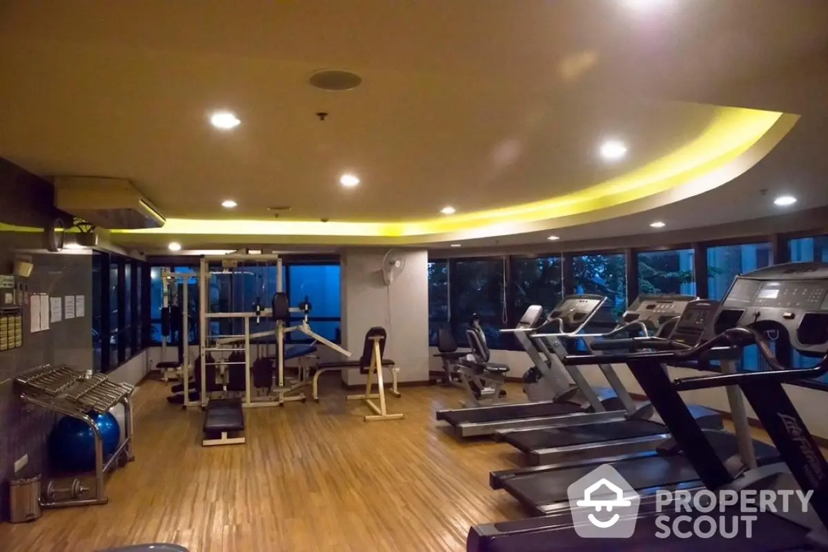 Spacious gym with modern fitness equipment and large windows for natural light