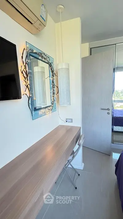 Modern bedroom with stylish decor, featuring a wall-mounted TV, sleek desk, and elegant lighting.