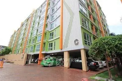 Modern apartment building with vibrant facade and parking area, ideal for urban living.
