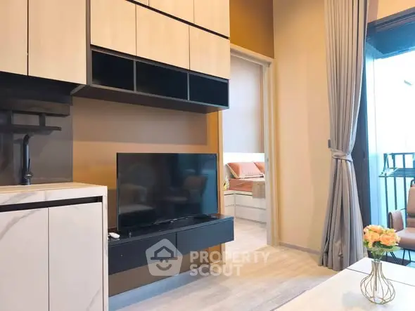 Modern living room with sleek TV setup and view into cozy bedroom, featuring elegant decor and natural light.