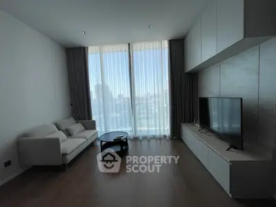 Modern living room with large windows and city view, featuring sleek furniture and natural light.