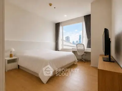 Modern bedroom with city view, featuring a cozy bed, sleek desk, and large window for natural light.