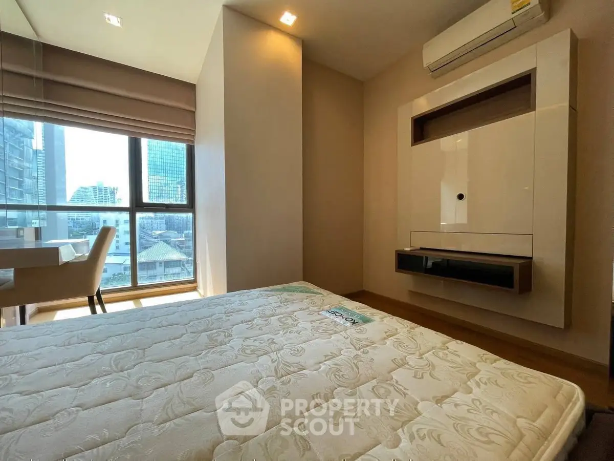 Modern bedroom with large window and city view, featuring air conditioning and stylish decor.