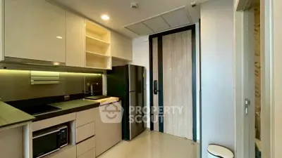 Modern kitchen with sleek cabinets, built-in microwave, and stainless steel fridge in a stylish apartment.