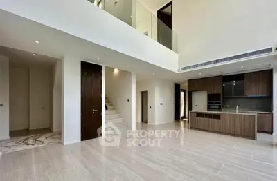 Spacious modern living room with open kitchen and elegant staircase in luxury home.