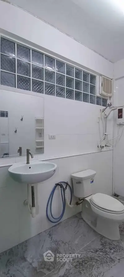 Modern bathroom with sleek fixtures and glass block window for natural light.