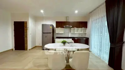 Modern open-layout kitchen with dining area, featuring sleek cabinetry and natural light.