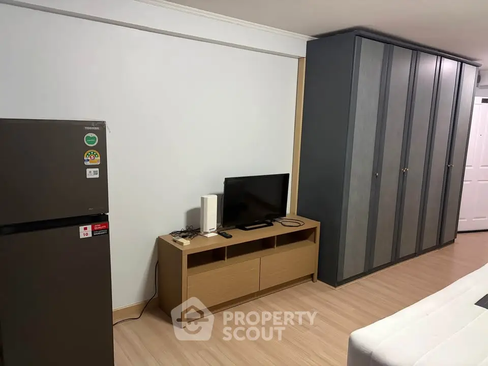 Modern apartment interior with sleek wardrobe and compact entertainment setup