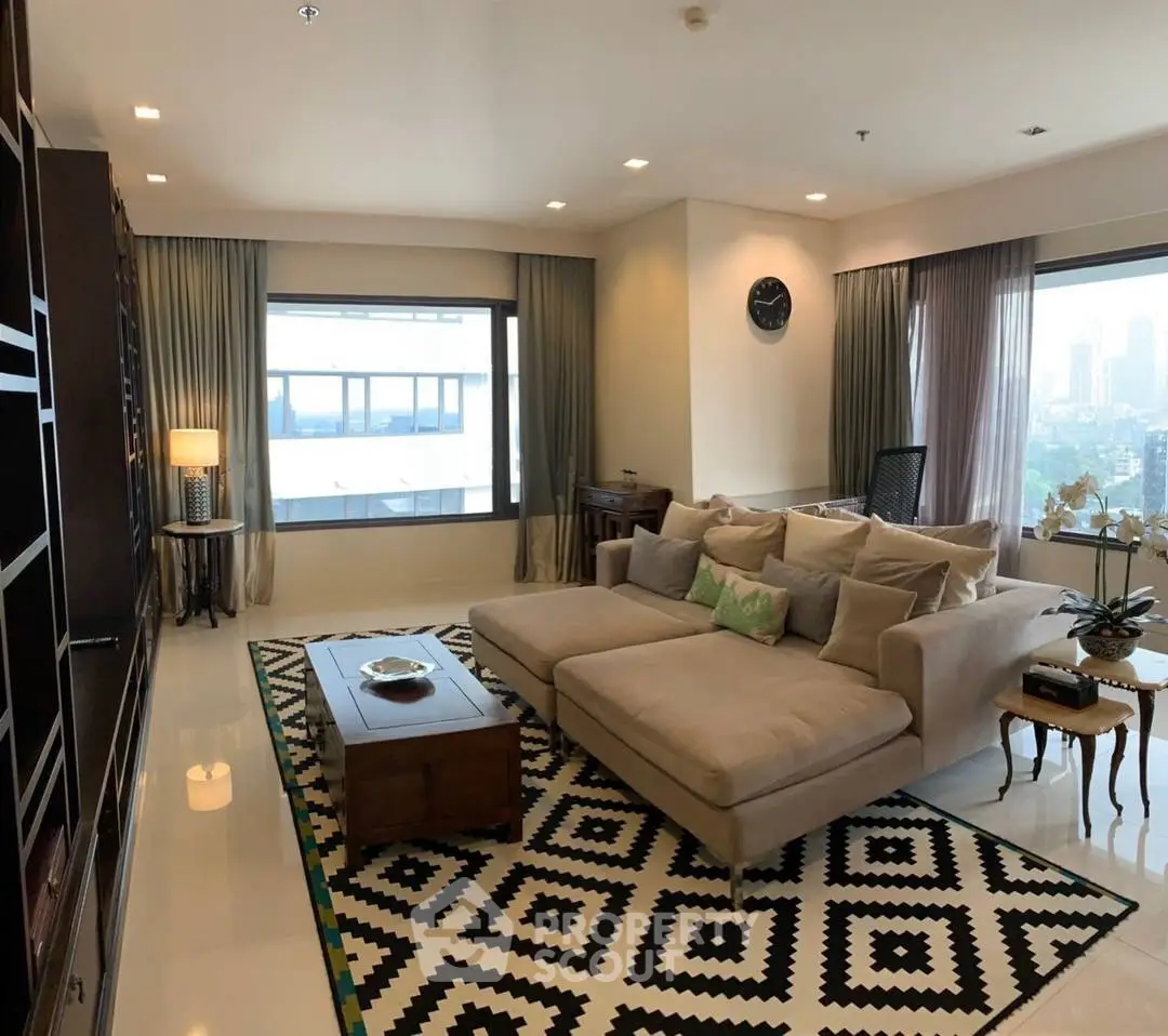 Spacious living room with modern decor and city view, featuring a large sofa and stylish rug.