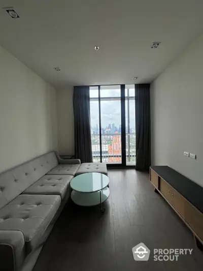 Modern living room with large window and city view, featuring sleek furniture and minimalist design.