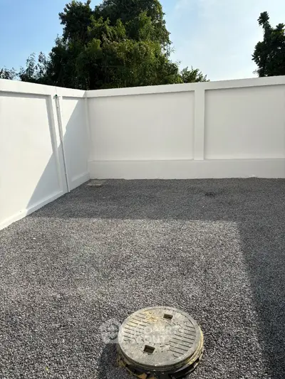 Spacious rooftop area with privacy wall and gravel flooring, perfect for outdoor activities.