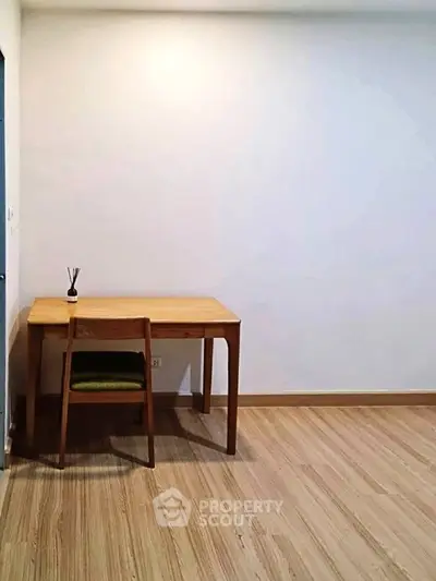 Minimalist study area with wooden desk and chair on light wood flooring.