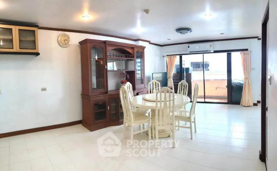 Spacious dining area with elegant wooden furniture and large windows leading to a balcony.