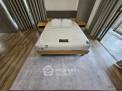 Modern bedroom with wooden flooring and large window for natural light