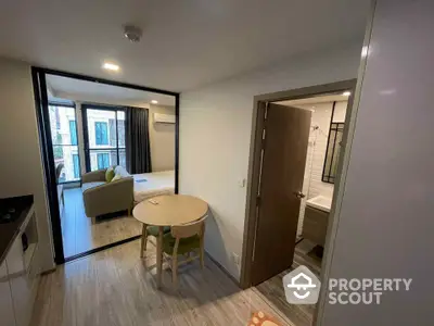 Modern apartment interior with open layout, featuring living area and bathroom access.